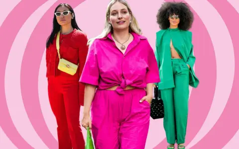 Drei Frauen in auffälligen, monochromen Outfits: Rot, Pink und Grün. Sie präsentieren selbstbewusst ihre Looks.