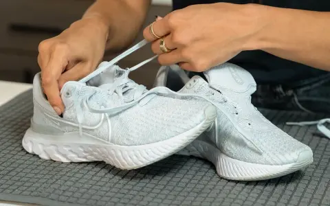 Hände binden hellblaue Nike Schuhe, bereit für die Waschmaschine.