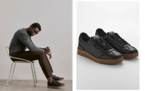 Mann sitzt nachdenklich auf einem Stuhl, trägt schwarze Sneaker mit brauner Sohle. So sollten Schuhe sitzen: bequem und stilvoll.