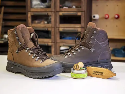 Braune Wanderschuhe, daneben ein Wachs und eine Bürste zur Pflege. So bleiben deine adidas Terrex Stiefel wie neu, auch nach der nächsten "Waschmaschine" aus Schlamm und Matsch.