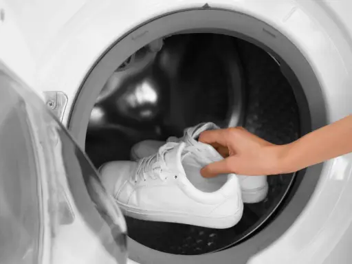 Weiße Sneaker werden in die Waschmaschine gelegt, um sie wieder sauber zu bekommen.