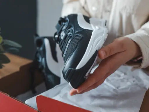 Schwarze und weiße Sneaker, die aus einer roten Box genommen werden. Sehen sie aus wie vapormax fake?