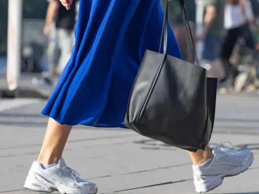 Ein blaues Kleid mit weißen Sneakern zum Kleid und einer schwarzen Tasche.