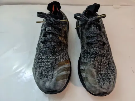 Zwei adidas bb3900 Laufschuhe mit grauem Camouflage-Muster und goldenen Streifen.