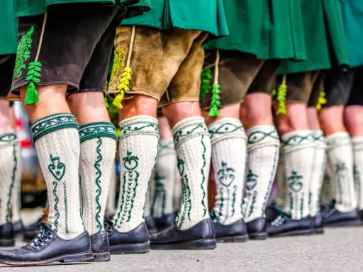 Herren in Lederhosen und traditionellen Strümpfen tragen passende Schuhe. Welche Schuhe zur Lederhose Herren? Schwarze Trachtenschuhe sind hier die Wahl.
