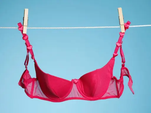 Ein roter BH mit Herzchen-Trägern trocknet an der Wäscheleine. Frisch gewaschen und bereit für den nächsten Einsatz.