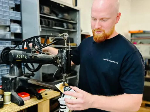 Ein Schuster repariert Schuhe an einer alten Nähmaschine. Er ist ein Handwerker, der sich um das Schuhwerk kümmert.