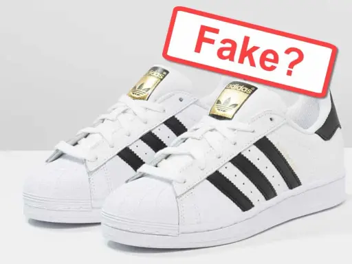 Weiße Adidas Sneaker mit schwarzen Streifen und goldenem Logo. Ein rotes Schild fragt: "Fake?". So kannst du Adidas Fake erkennen.