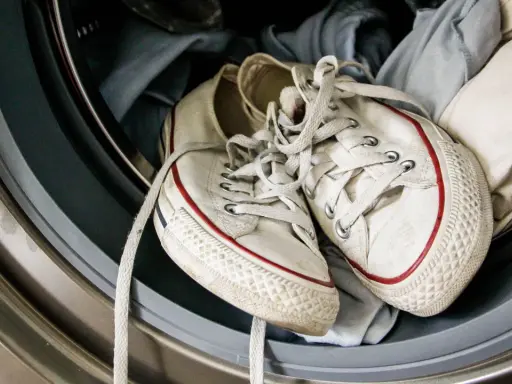 Weiße Superga Schuhe mit roten Streifen warten in der Waschmaschine auf ihren Waschgang.
