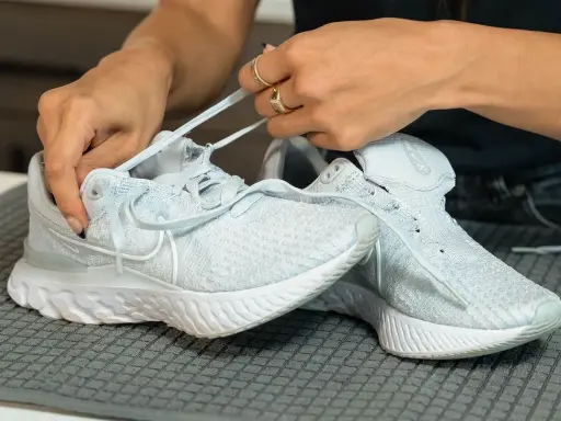 Hände binden hellblaue Nike Schuhe, bereit für die Waschmaschine.