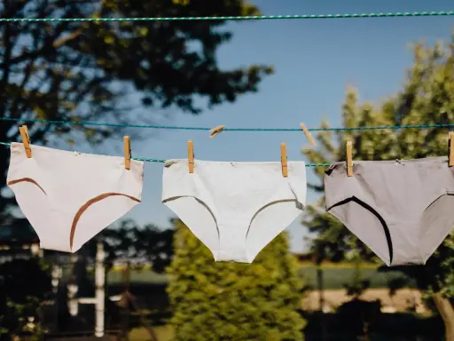 Drei Unterhosen in verschiedenen Grautönen trocknen an einer Wäscheleine. Ein Zeichen für frische Wäsche nach dem unterhosen waschen.