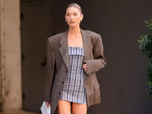 Frau in kariertem Blazer und gestreiftem Kleid. Der Blazer ist leicht zerknittert, als ob sie ihn gerade aus der Wäsche genommen hätte.