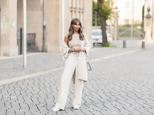 Eine Frau in einem cremefarbenen Outfit mit weiten Leinenhosen, das perfekt für den Sommer ist. So kann man Leinenhose kombinieren Damen!