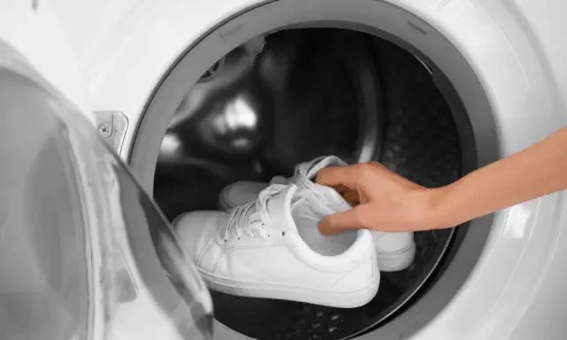 Weiße Sneaker werden in die Waschmaschine gelegt, um sie wieder sauber zu bekommen.