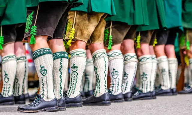 Herren in Lederhosen und traditionellen Strümpfen tragen passende Schuhe. Welche Schuhe zur Lederhose Herren? Schwarze Trachtenschuhe sind hier die Wahl.