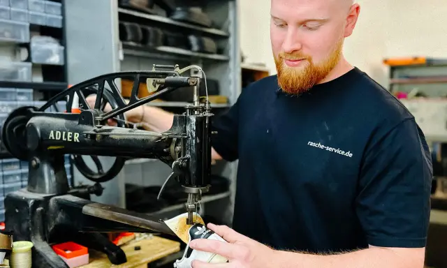 Ein Schuster repariert Schuhe an einer alten Nähmaschine. Er ist ein Handwerker, der sich um das Schuhwerk kümmert.