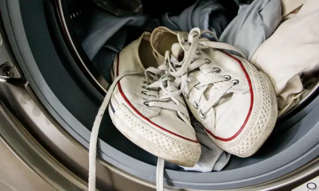 Weiße Superga Schuhe mit roten Streifen warten in der Waschmaschine auf ihren Waschgang.