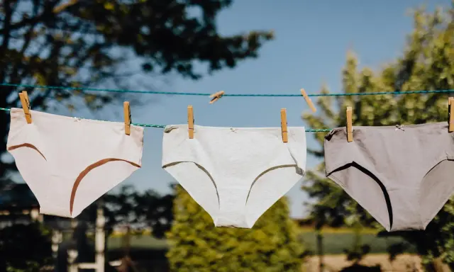 Drei Unterhosen in verschiedenen Grautönen trocknen an einer Wäscheleine. Ein Zeichen für frische Wäsche nach dem unterhosen waschen.