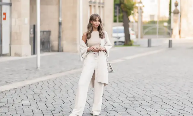 Eine Frau in einem cremefarbenen Outfit mit weiten Leinenhosen, das perfekt für den Sommer ist. So kann man Leinenhose kombinieren Damen!