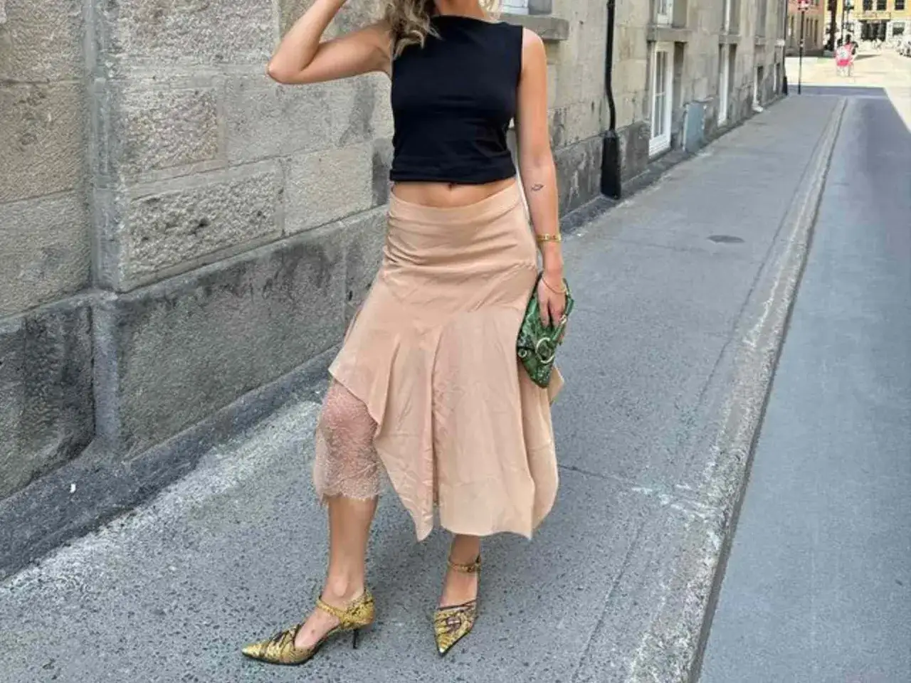 Ein beiger Satinrock kombiniert mit schwarzem Crop-Top und auff&auml;lligen Schuhen.