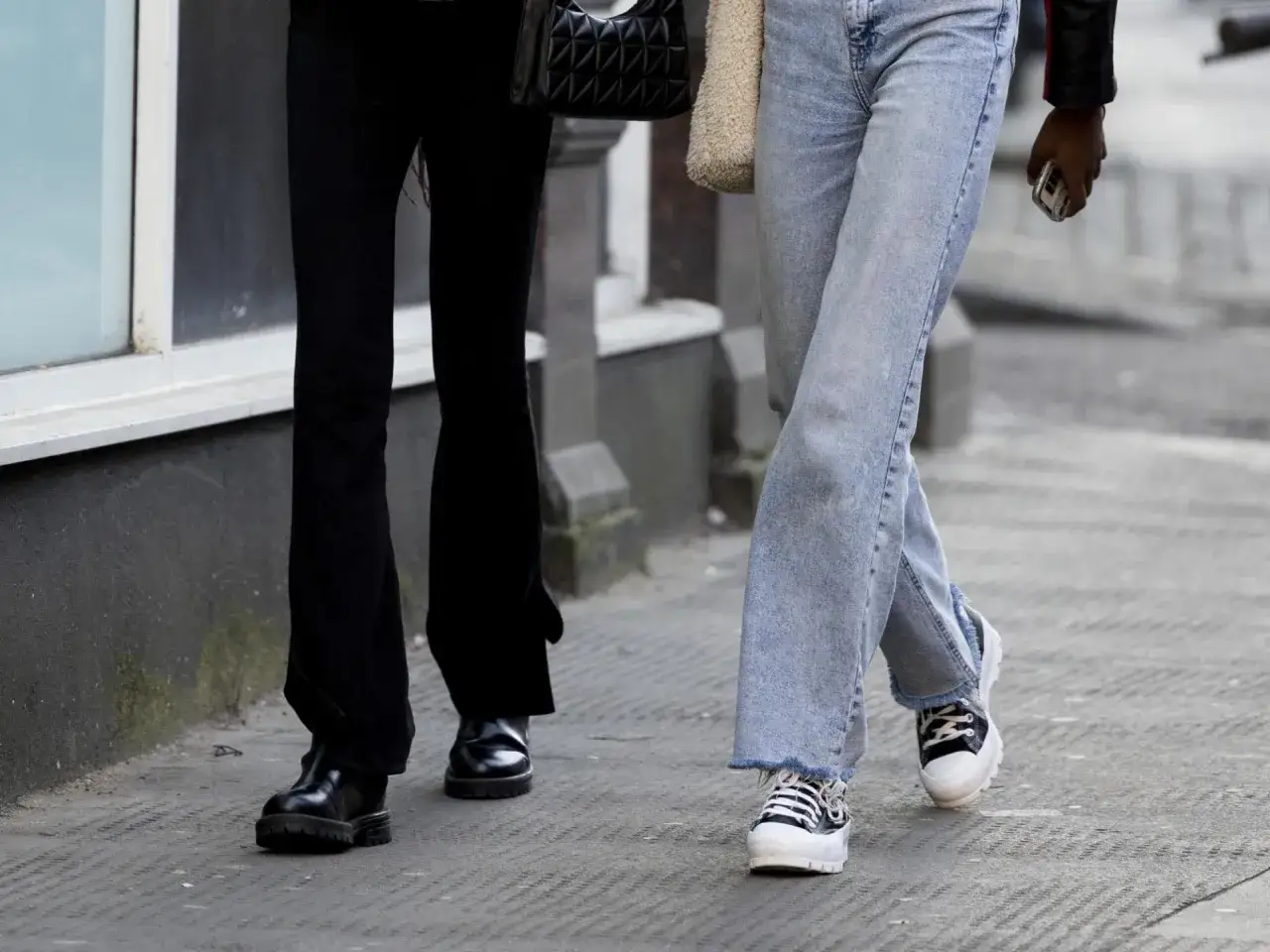 Zwei Damen zeigen, wie man hohe Chucks kombiniert: eine mit lässiger Jeans, die andere mit eleganten schwarzen Hosen.