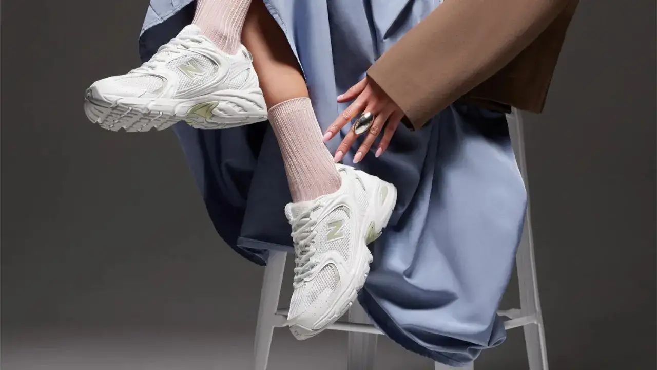 Weiße New Balance 530 Sneaker mit hellgrünen Akzenten, getragen mit rosafarbenen Socken. Perfekt für den lässigen Look, auch wenn man sie waschen muss.