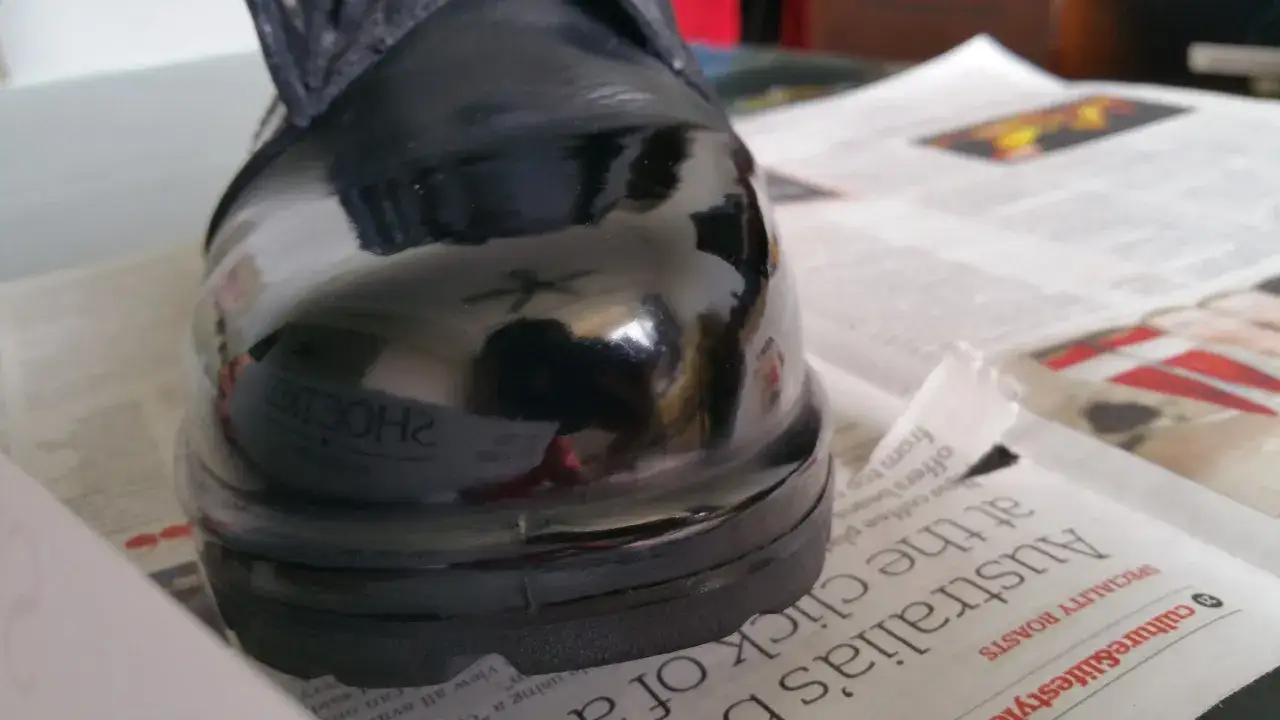 Gl&auml;nzender schwarzer Schuh, der auf Zeitungspapier steht. Perfekt, um zu zeigen, wie man Lackschuhe pflegen kann.