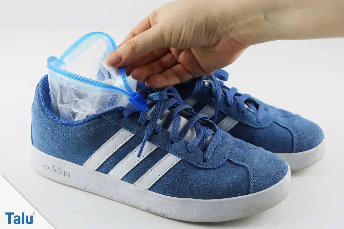 Blaue Sneaker, die vorne zu eng sind, werden mit einem Gefrierbeutel gedehnt.