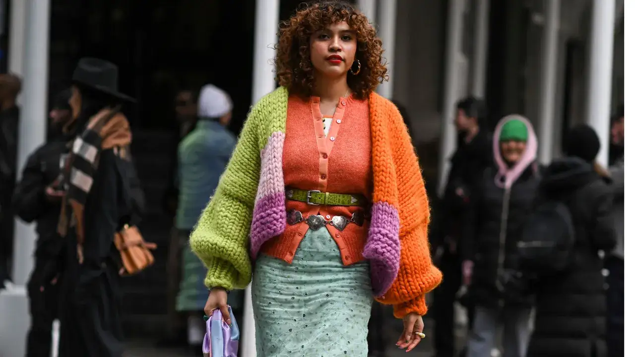 Bunte Strickjacke mit Ballonärmeln, die zeigt, wie man einen Cardigan kombiniert, Damen tragen dazu mintgrünen Rock und auffälligen Gürtel.