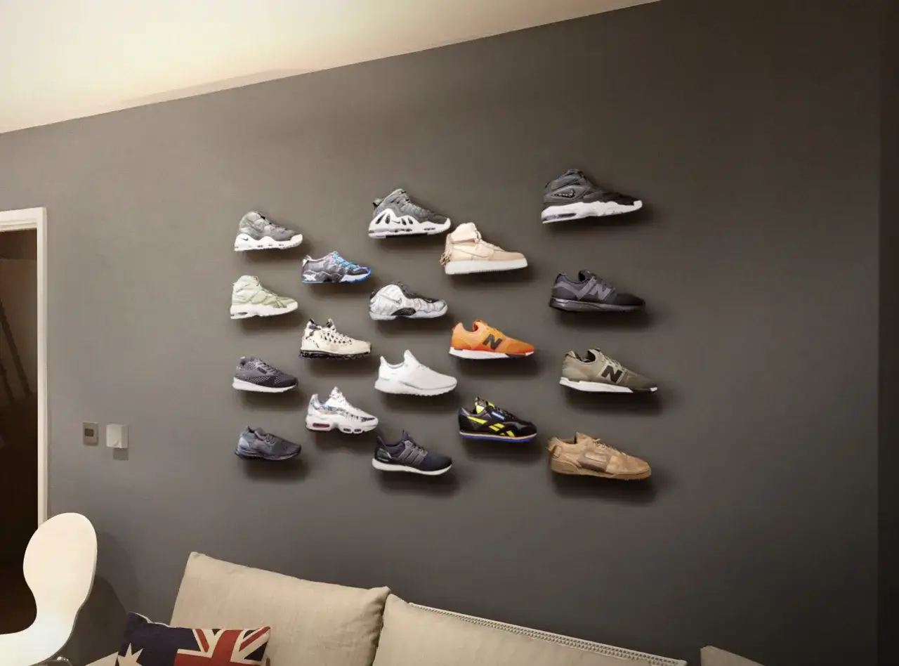 Eine Wand im Sneaker Zimmer, dekoriert mit zahlreichen Turnschuhen in verschiedenen Farben und Modellen, die wie Kunstwerke pr&auml;sentiert werden.