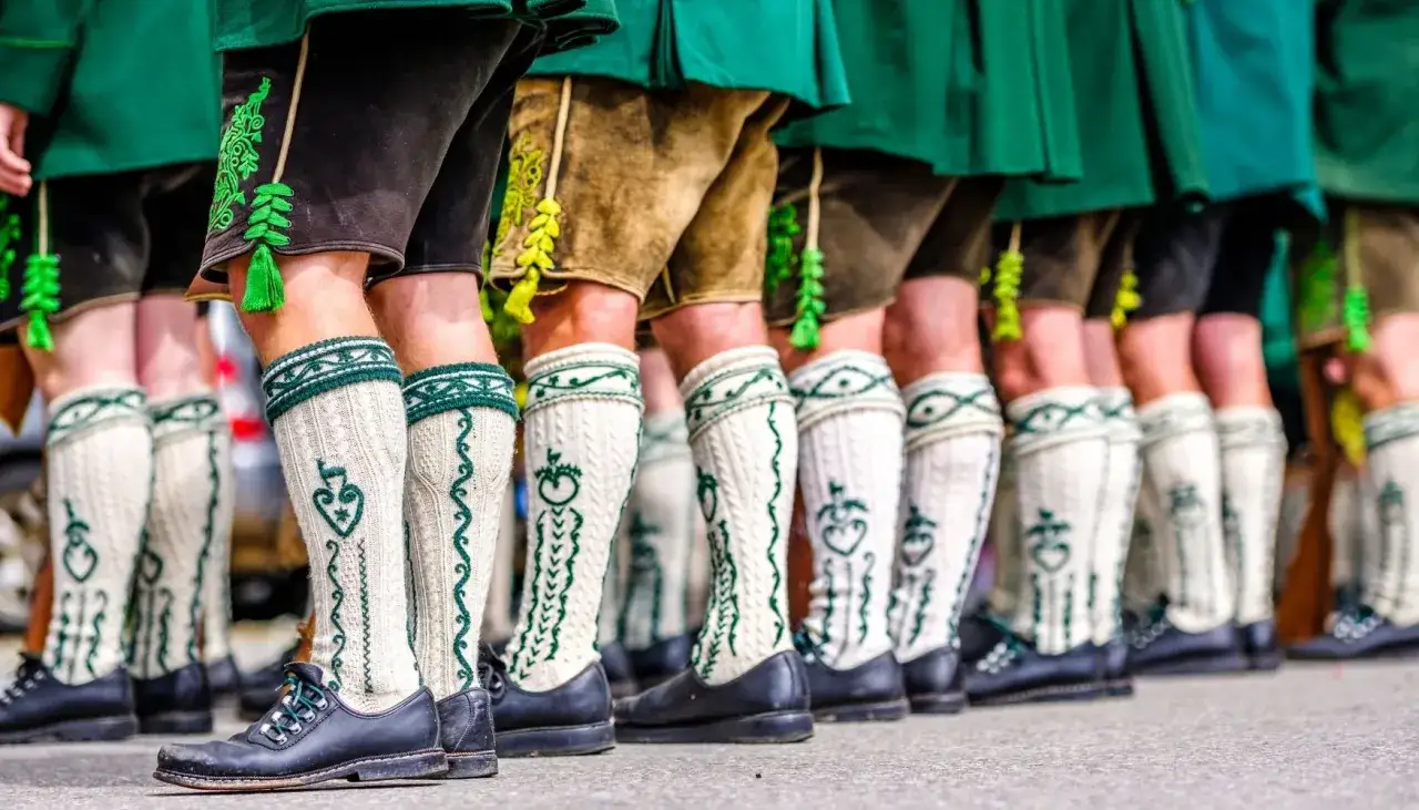 Herren in Lederhosen und traditionellen Str&uuml;mpfen tragen schwarze Schuhe. Die Frage 