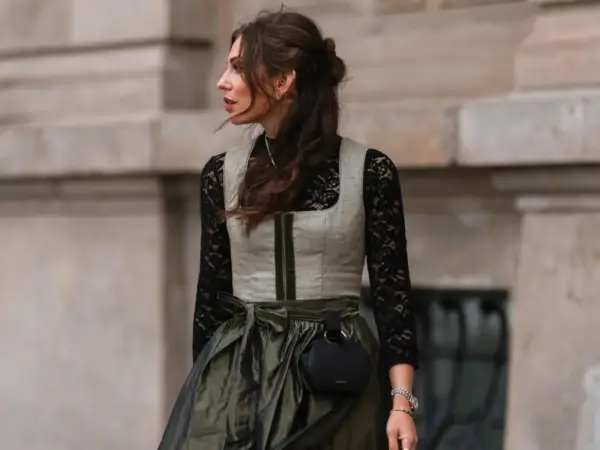 Eine Frau trägt eine graue Weste über einer schwarzen Spitzenbluse. So lässt sich die schwarze Bluse kombinieren für einen modernen Look.